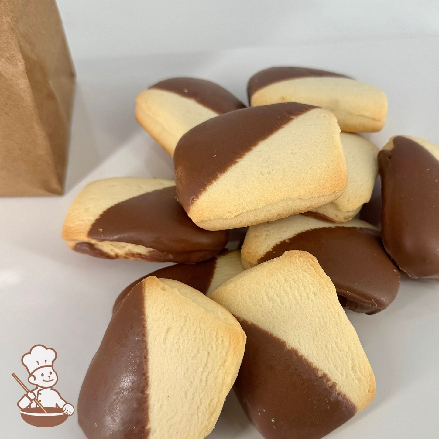 Ten butter shortbread cookies, each half-dipped in Belgian chocolate, are arranged in front of a kraft window bag.