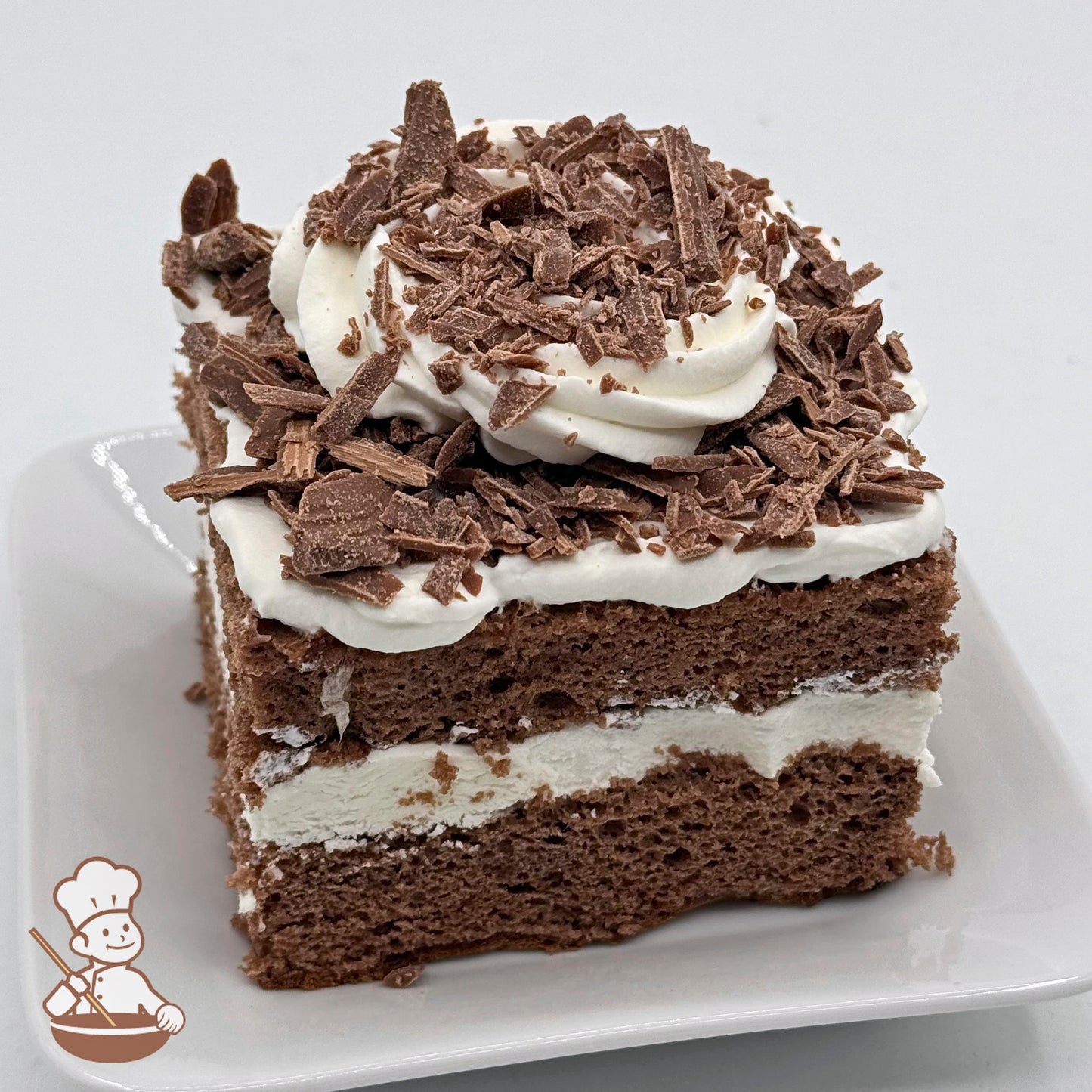 A slice of chocolate chiffon cake with whipped cream, topped with Belgian chocolate shavings.