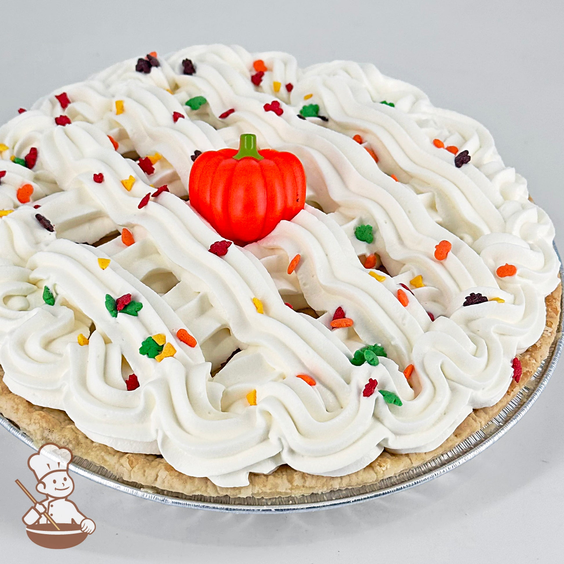 A pumpkin chiffon cream pie topped with whipped cream swirls, colorful fall-themed sprinkles, and a small pumpkin decoration at the center.