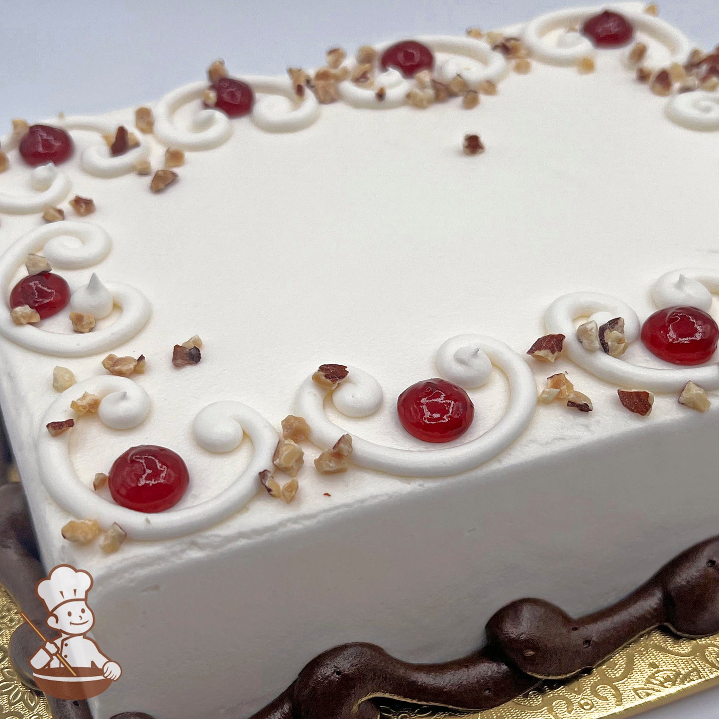 White sheet cake decorated with buttercream scrolls, raspberry preserve dots, diced almonds, and a piped brown base.