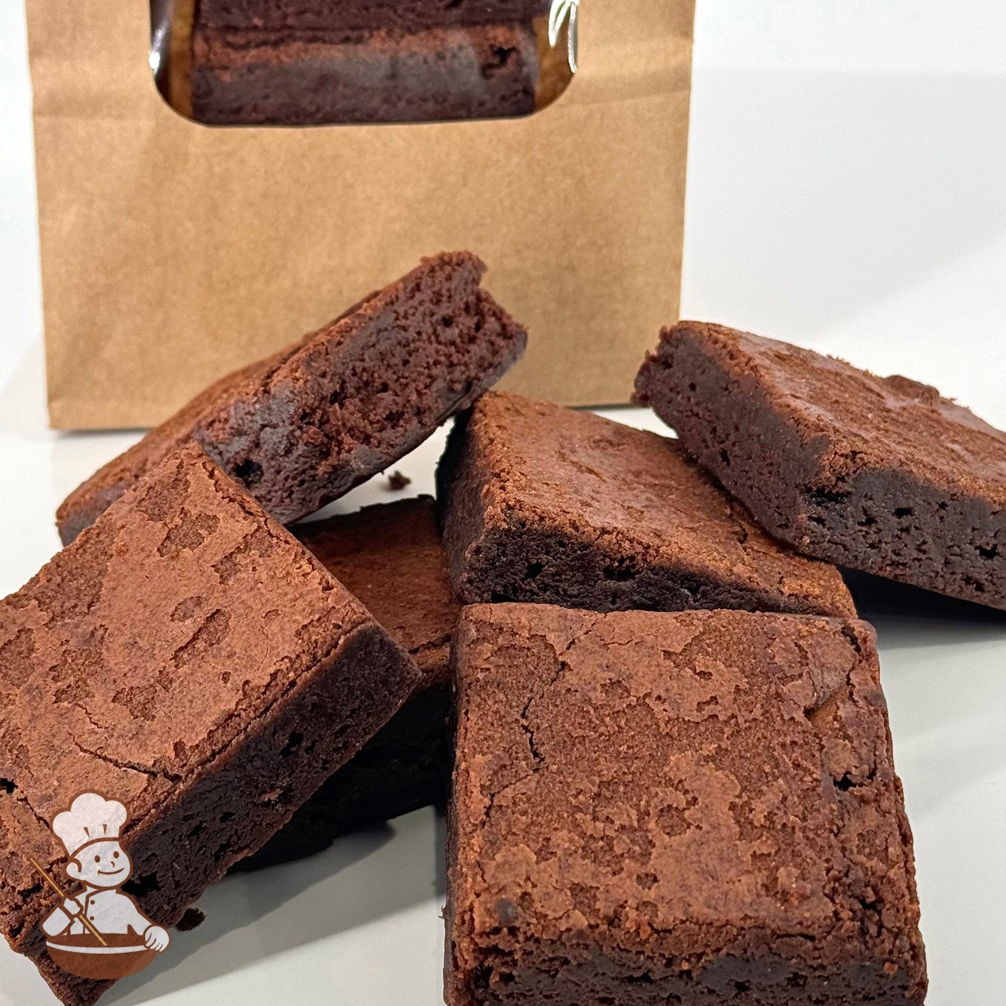 Six chocolate brownies made with Belgian chocolate are arranged in front of a kraft window bag.