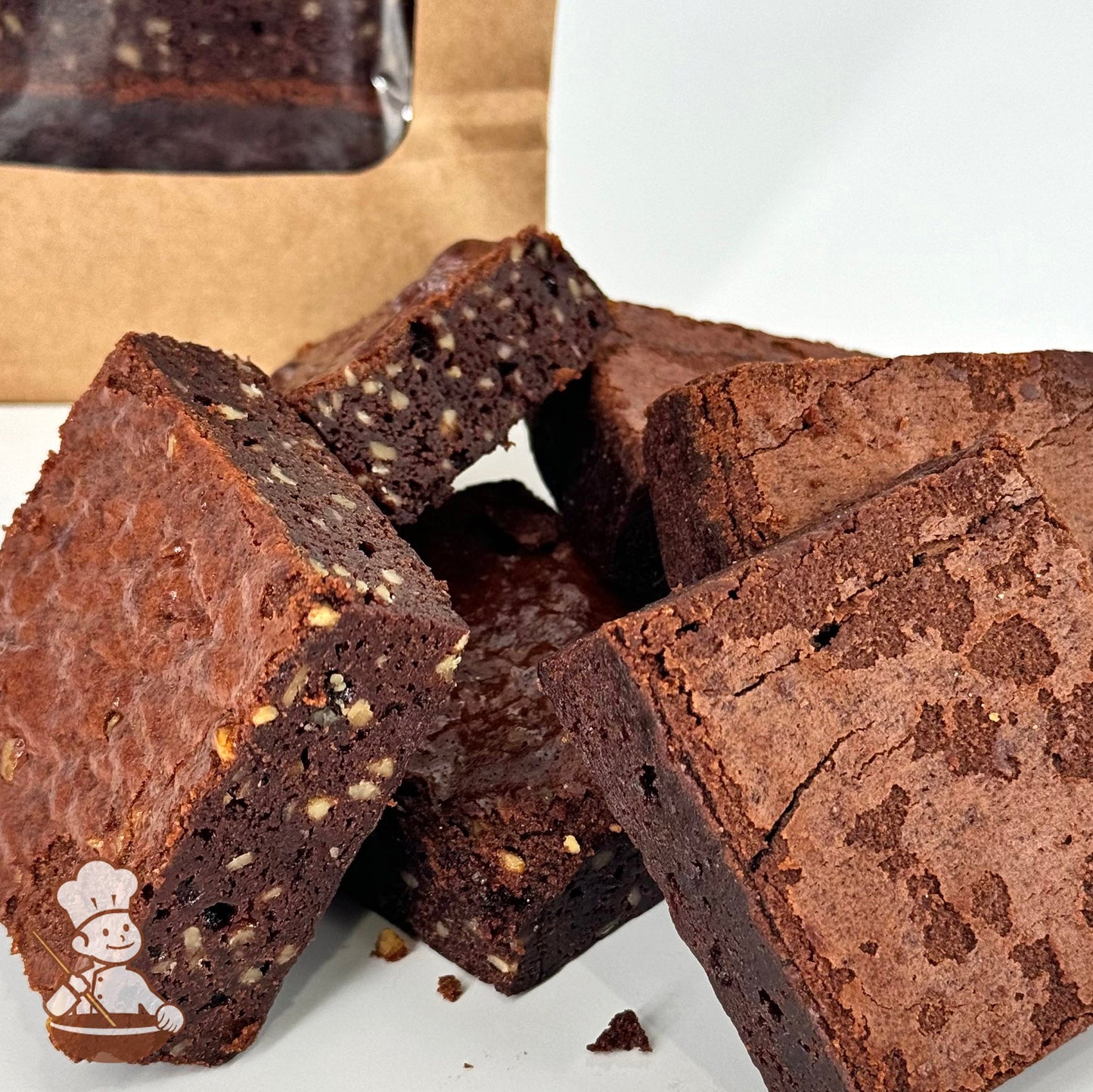 Three Belgian chocolate brownies and three Belgian chocolate brownies with walnuts are arranged together in front of a kraft window bag.