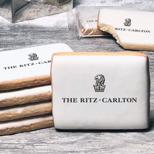 A stack of rectangle butter shortbread cookies with Ritz Carlton logo printed directly on a white, lemon sugar icing.