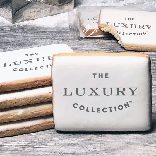 A stack of rectangle butter shortbread cookies with The Luxury Collection logo printed directly on a white, lemon sugar icing.