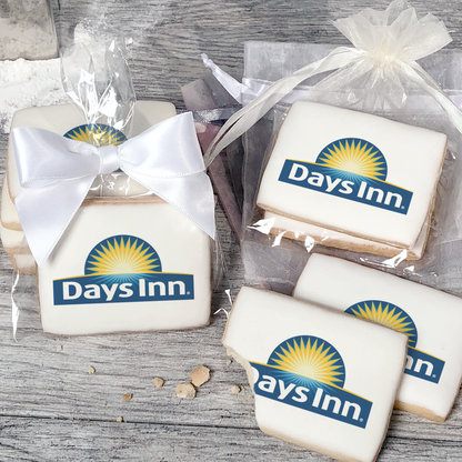 A stack of rectangular butter shortbread cookies with Days Inn logo printed directly on a white, light sugar icing. Some cookies are shown in clear packaging with a twist-tie ribbon bow or inside an organza bag.