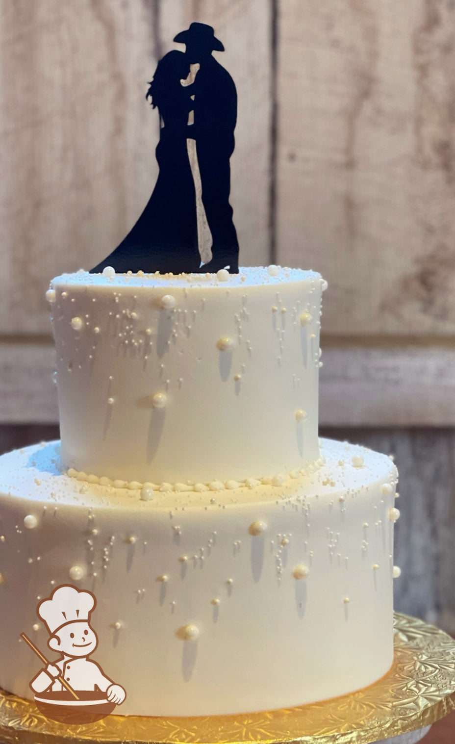 2-tier cake with smooth white icing and decorated with small and big white sugar pearls.