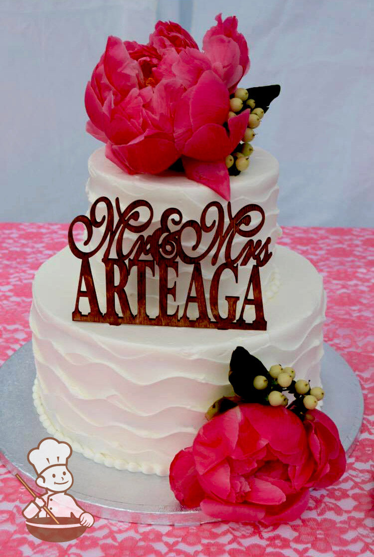 2-tier cake with white icing and decorated with a wavy texture and white beaded trims.