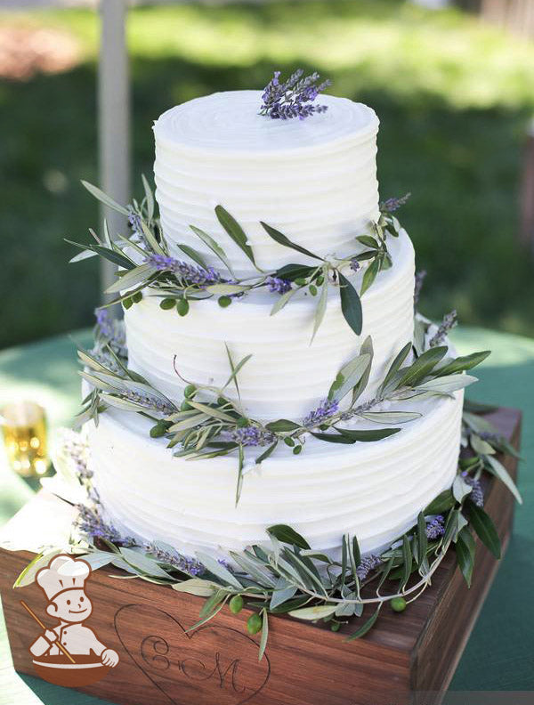 3-tier cake with white icing and decorated with a horizontal texture and lavender plants and vines.