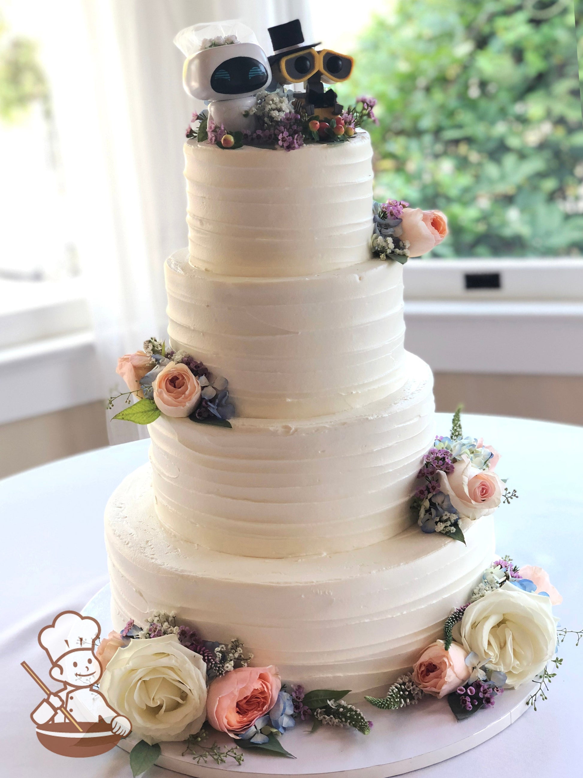 4-tier cake with white icing and decorated with a horizontal texture and fresh flowers.