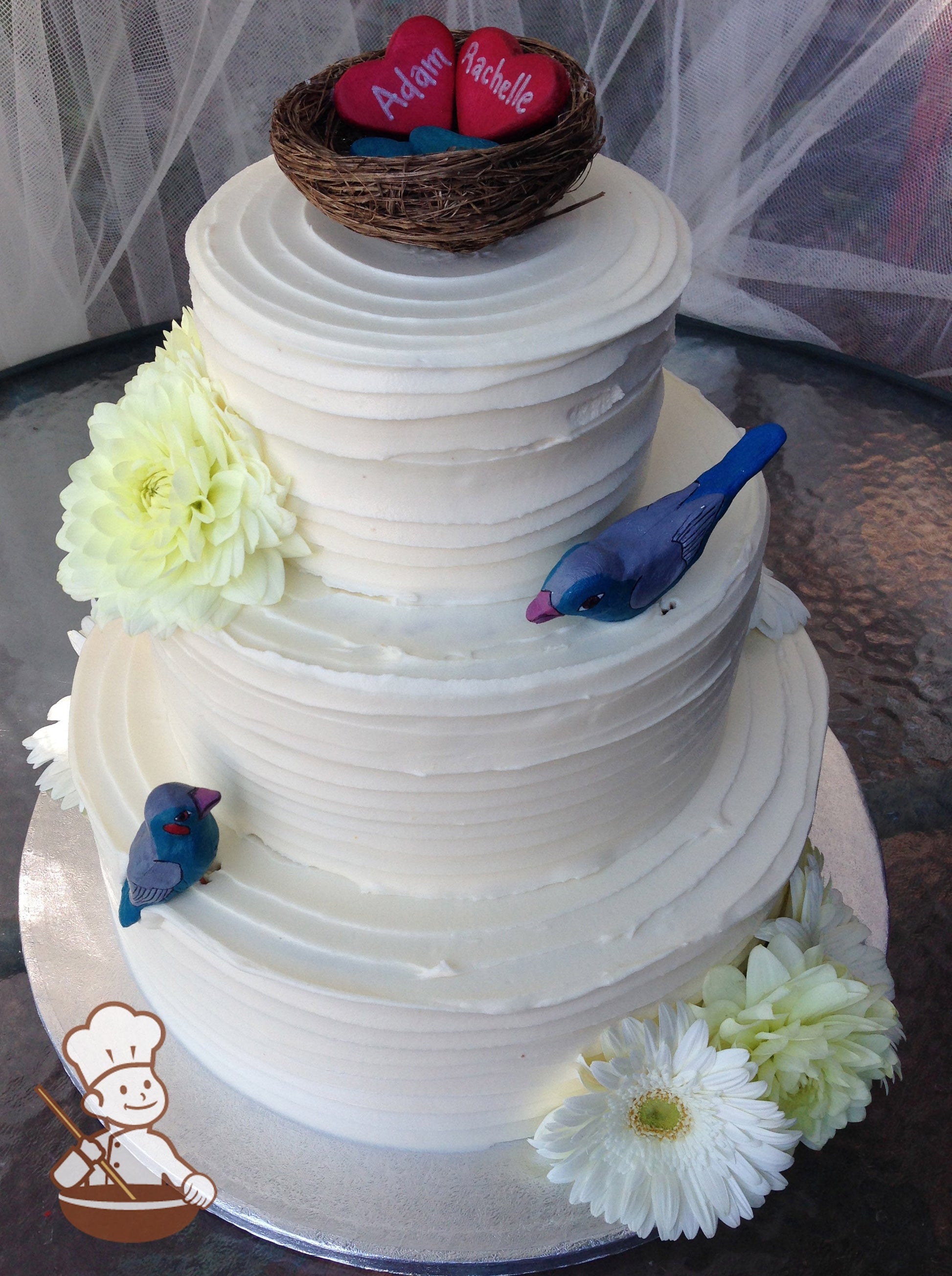 3-tier cake with white icing and decorated with a horizontal texture and fresh flowers in white and yellow colors.