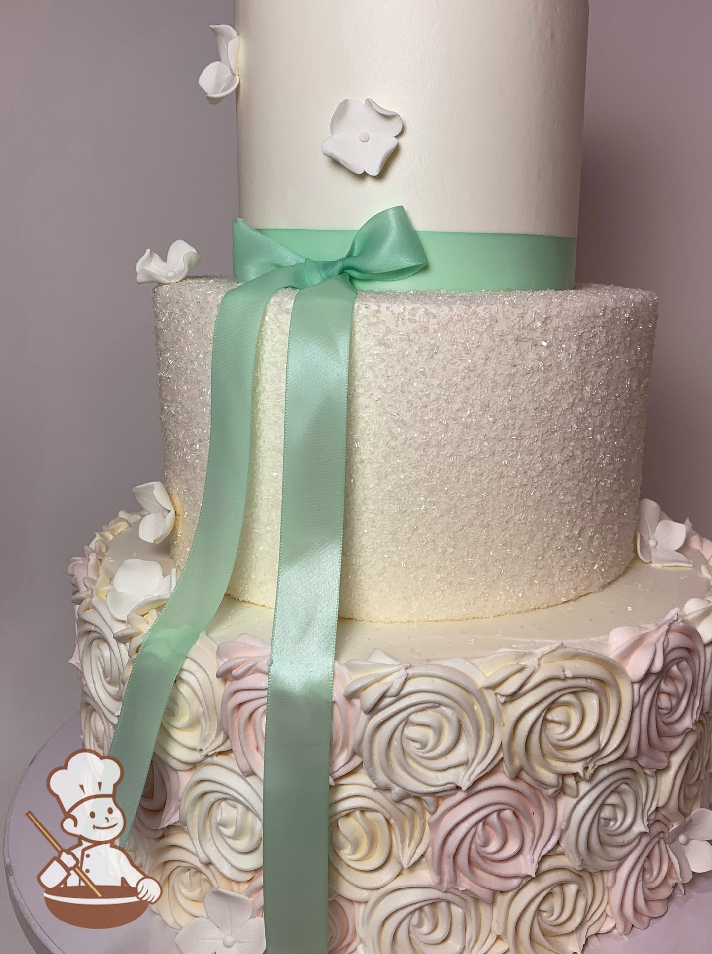 3 tier round wedding cake with multi color rosette swirls on base & sugar crystal covered middle tier & finished with satin bow & sugar flowers.