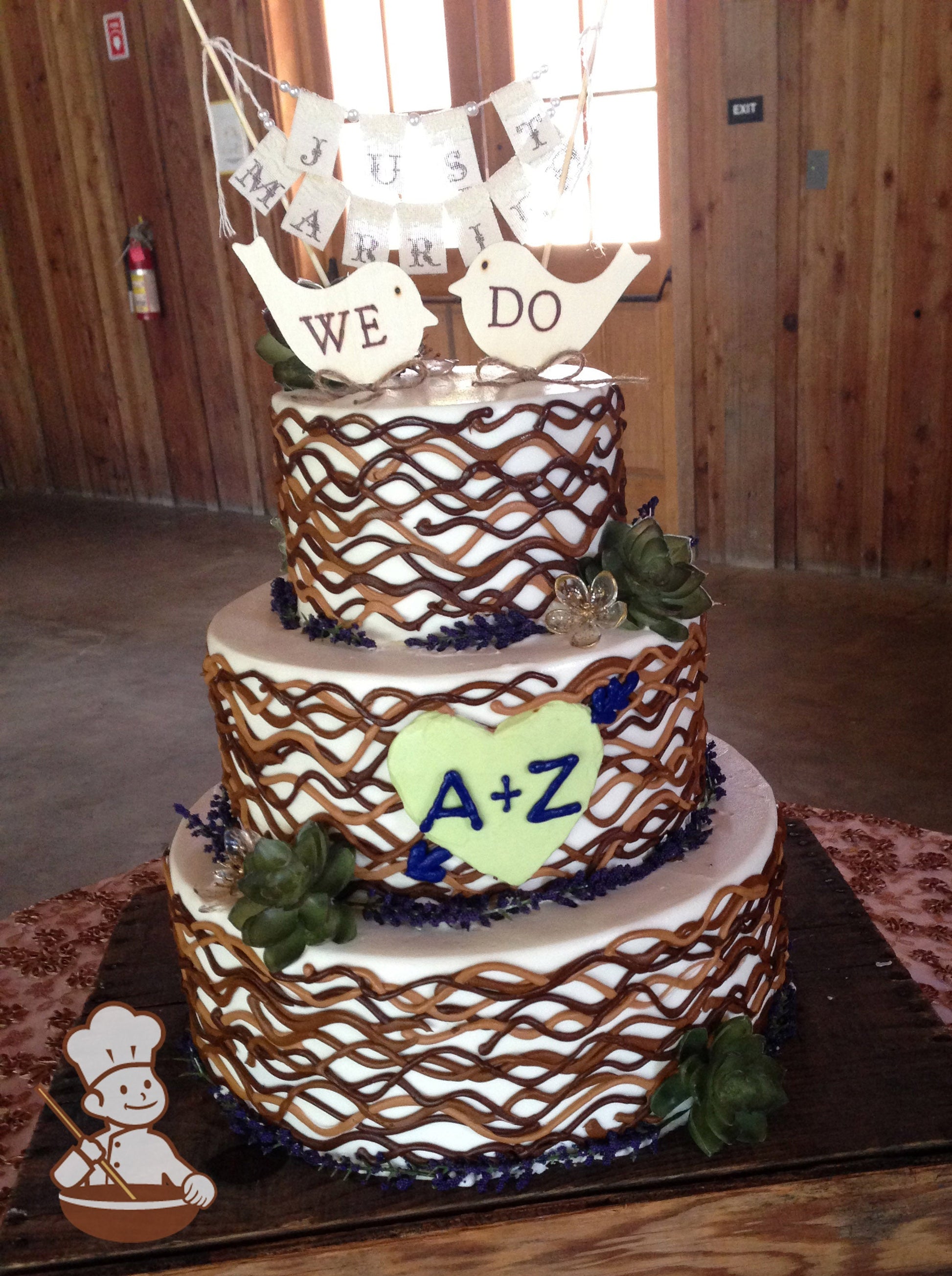 3-tier cake with smooth white icing and decorated with wavy buttercream lines in different shades of brown and succulent plants.