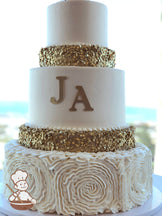 Cake decorated with white buttercream ruffles, gold sequins and a gold monogram.